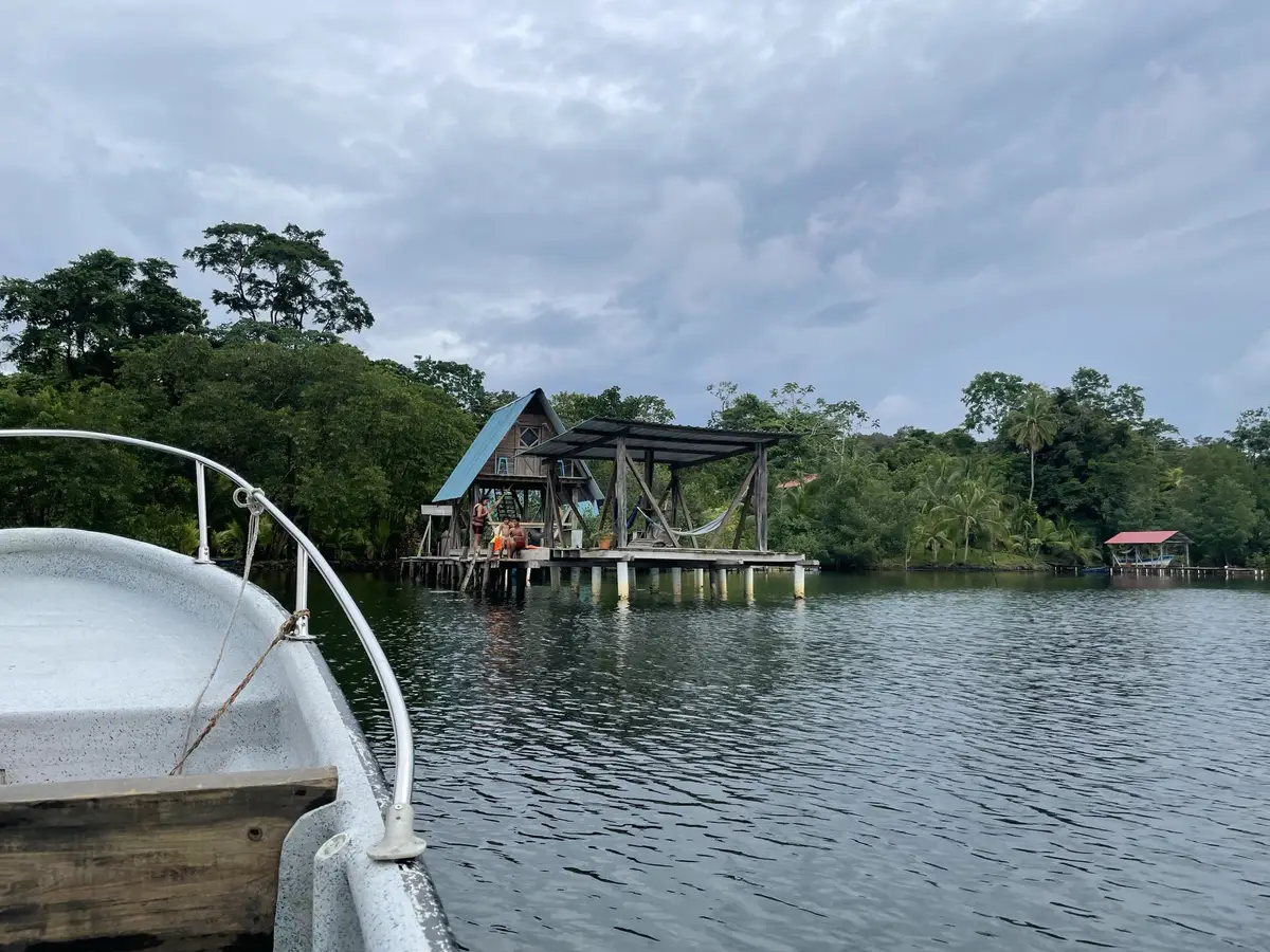 View from a boat toward an over-water cabin on a calm bay