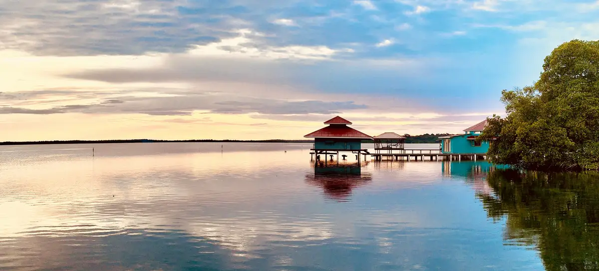 Over-water gazebo reflected in a still bay at sunset