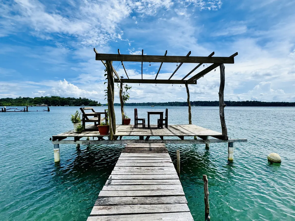 Wooden over-water deck with a table and chairs above turquoise water